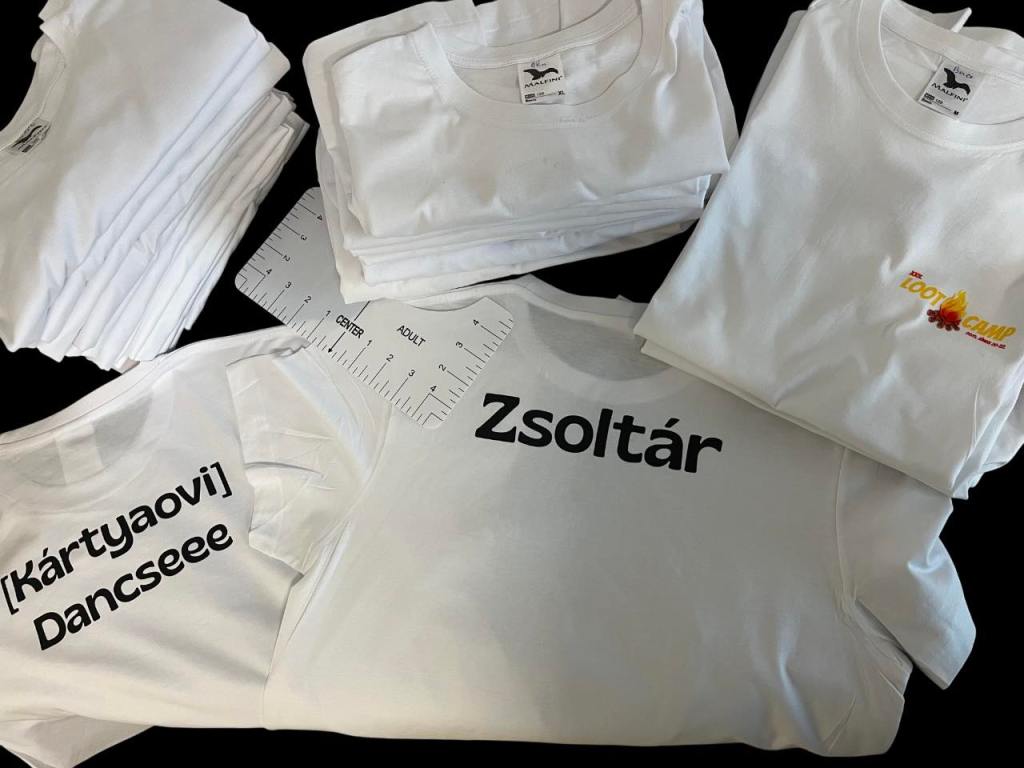 The image features four white t-shirts with varying designs, accompanied by a ruler on a black background.